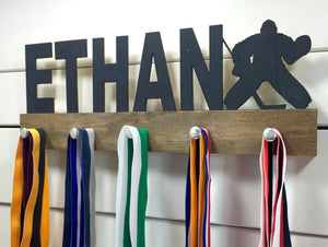  Our personalized hockey goalie medal holder is a unique gift for the goalie in your life. This display will be the perfect way for them to show off all of their well-deserved awards. This design comes in a variety of colors, or you can pick from our other choices of sports or phrases so we can customize it just the way you want!