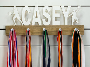 Our personalized basketball medal holder is a unique gift for the b-baller in your life. This display will be the perfect way for him to show off all of his awards. This design comes in a variety of colors, or you can pick from our other choices of sports or phrases so we can customize it just the way you want!