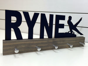 Our personalized gymnastics medal holder is a unique gift for the gymnast in your life. This display will be the perfect way for him to show off all of his well-deserved awards. This design comes in a variety of colors, or you can pick from our other choices of sports or phrases so we can customize it just the way you want!