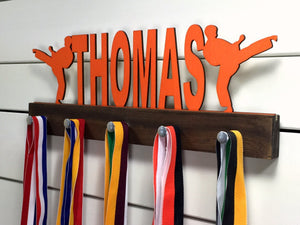 Our personalized martial arts medal holder is a unique gift for the fighter in your life. This display will be the perfect way for them to show off all of their well-deserved awards. This design comes in a variety of colors, or you can pick from our other choices of sports or phrases so we can customize it just the way you want!