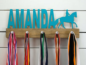 Our personalized equestrian medal holder is a unique gift for the horse-lover in your life. This display will be the perfect way for them to show off all of their well-deserved awards. This design comes in a variety of colors, or you can pick from our other choices of sports or phrases so we can customize it just the way you want!