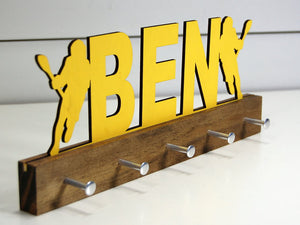 Our personalized lacrosse medal holder is a unique gift for the lacrosse player in your life. This display will be the perfect way for him to show off all of his well-deserved awards. This design comes in a variety of colors, or you can pick from our other choices of sports or phrases so we can customize it just the way you want!