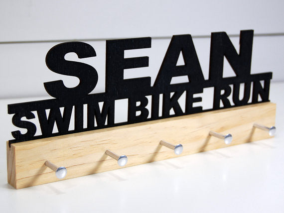 Our personalized triathlon medal holder is a unique gift for any triathlete so they can display all of their awesome and well-deserved awards. This design comes in a variety of colors, or you can pick from our other choices of sports or phrases so we can customize it just the way you want!