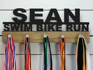 Our personalized triathlon medal holder is a unique gift for any triathlete so they can display all of their awesome and well-deserved awards. This design comes in a variety of colors, or you can pick from our other choices of sports or phrases so we can customize it just the way you want!
