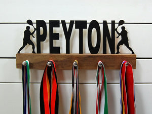 Our personalized tennis medal holder is a unique gift for the tennis player in your life. This display will be the perfect way for him to show off all of his well-deserved awards. This design comes in a variety of colors, or you can pick from our other choices of sports or phrases so we can customize it just the way you want!