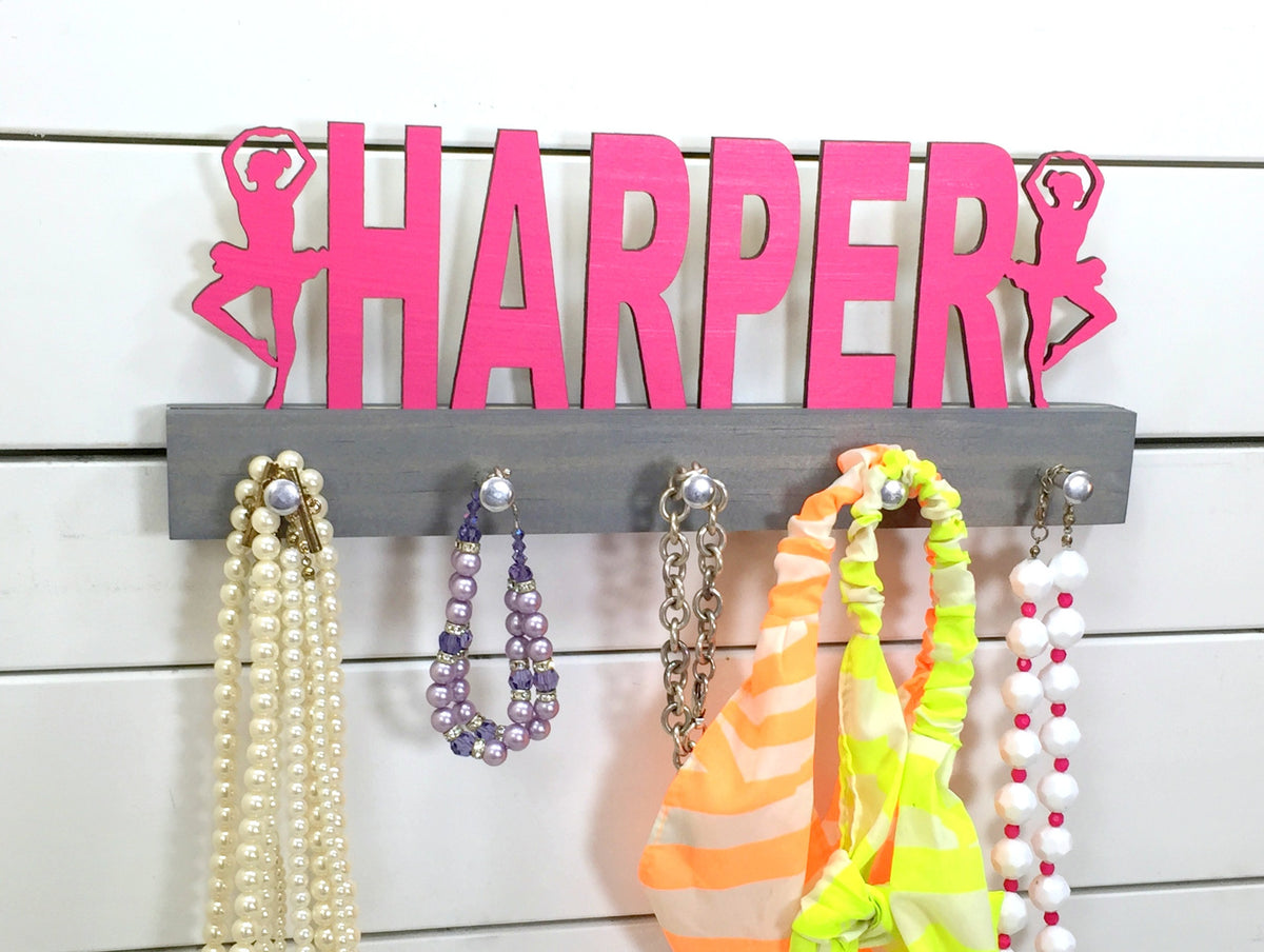 Our personalized ballerina medal holder is a unique gift for the dancer in your life. Whether she has awards to show off or just needs a place to organize her ribbons and jewelry, this display will get the job done. This design comes in a variety of colors, or you can pick from our other choices of sports or phrases so we can customize it just the way you want!