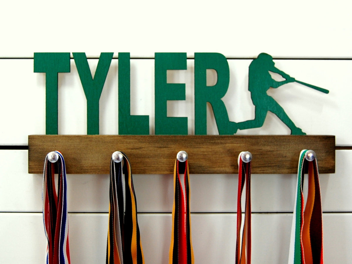  Our personalized baseball medal holder is a unique gift for the ballplayer in your life. This display will be the perfect way for him to show off all of his awards. This design comes in a variety of colors, or you can pick from our other choices of sports or phrases so we can customize it just the way you want!