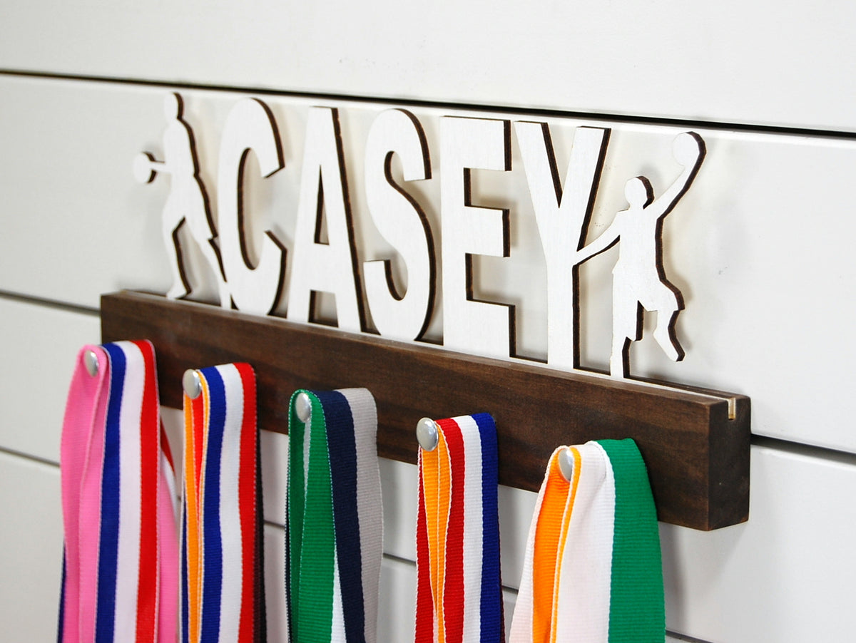  Our personalized basketball medal holder is a unique gift for the b-baller in your life. This display will be the perfect way for him to show off all of his awards. This design comes in a variety of colors, or you can pick from our other choices of sports or phrases so we can customize it just the way you want!