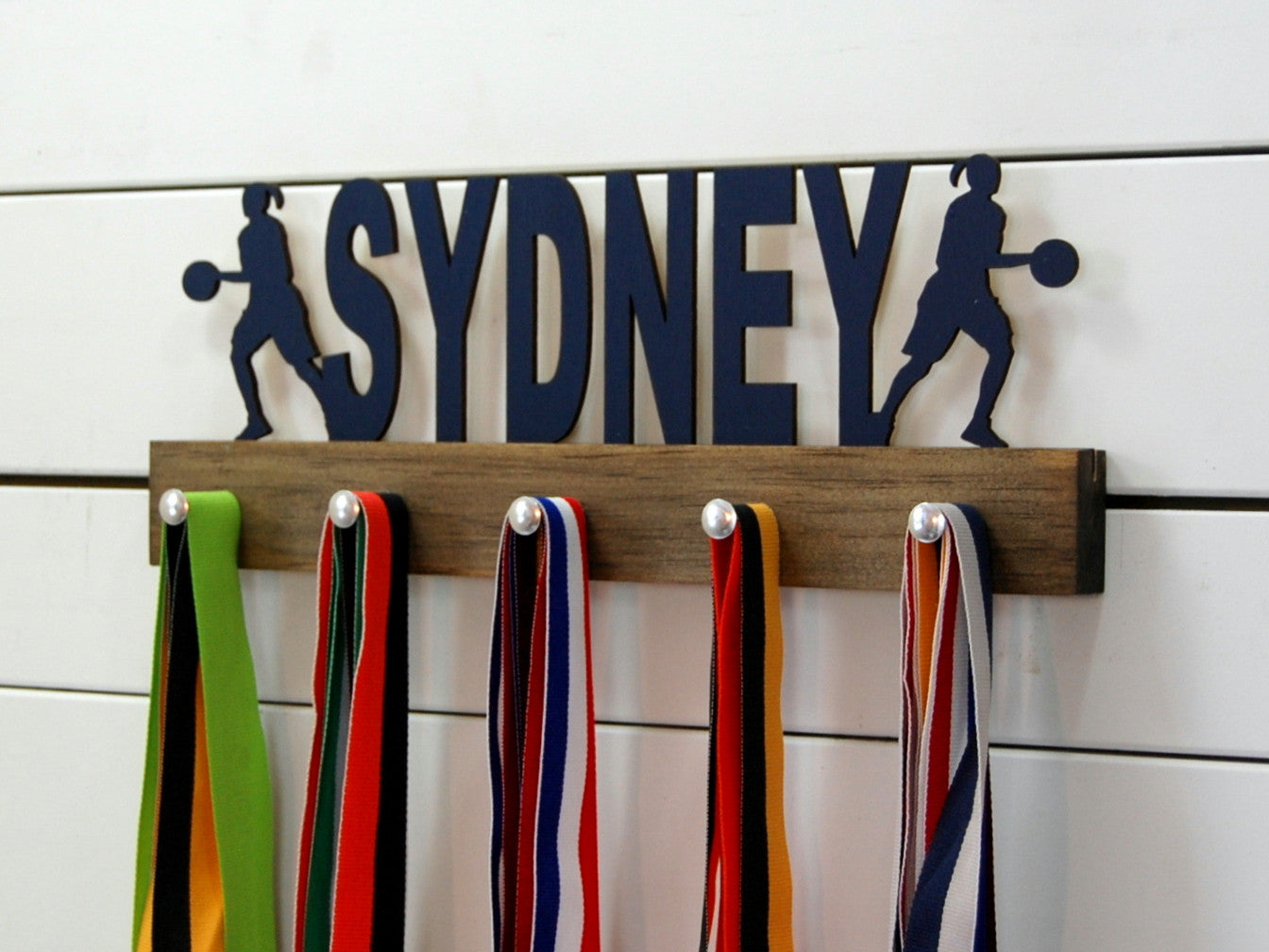  Our personalized basketball medal holder is a unique gift for the b-baller in your life. This display will be the perfect way for her to show off all of her awards. This design comes in a variety of colors, or you can pick from our other choices of sports or phrases so we can customize it just the way you want!