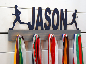 Our personalized running medal holder is a great gift for your runner boy so he can display all of his awesome awards. This design comes in a variety of colors, or you can pick from our other choices of sports or phrases so we can customize it just the way you want!