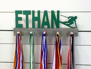 Our personalized skiing medal holder is a unique gift for the skier in your life. This display will be the perfect way for them to show off all of their well-deserved awards. This design comes in a variety of colors, or you can pick from our other choices of sports or phrases so we can customize it just the way you want!