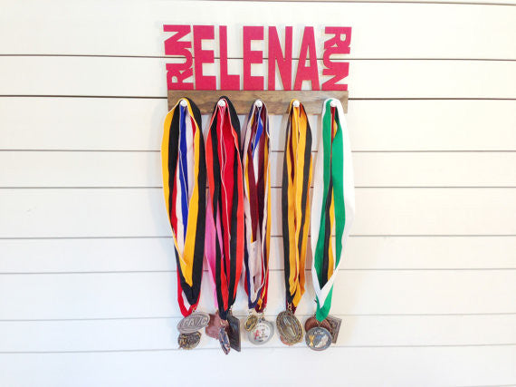 Our personalized running medal holder is a great gift for any runner so they can display all of their awesome awards. This design comes in a variety of colors, or you can pick from our other choices of sports or phrases so we can customize it just the way you want!
