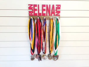 Our personalized running medal holder is a great gift for any runner so they can display all of their awesome awards. This design comes in a variety of colors, or you can pick from our other choices of sports or phrases so we can customize it just the way you want!