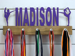  Our personalized dance medal holder is a unique gift for the dancer in your life. This display will be the perfect way for them to show off all of their well-deserved awards. This design comes in a variety of colors, or you can pick from our other choices of sports or phrases so we can customize it just the way you want!