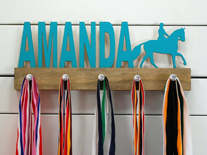  Our personalized equestrian medal holder is a unique gift for the horse-lover in your life. This display will be the perfect way for them to show off all of their well-deserved awards. This design comes in a variety of colors, or you can pick from our other choices of sports or phrases so we can customize it just the way you want!