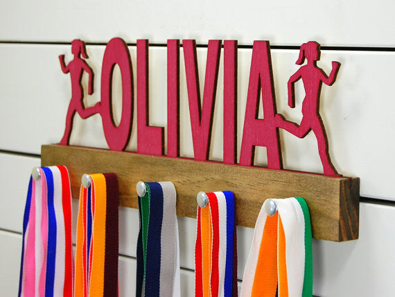  Our personalized running medal holder is a great gift for your runner girl so she can display all of her awesome awards. This design comes in a variety of colors, or you can pick from our other choices of sports or phrases so we can customize it just the way you want!