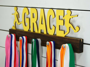 Our personalized soccer medal holder is a unique gift for the soccer player in your life. This display will be the perfect way for her to show off all of her well-deserved awards. This design comes in a variety of colors, or you can pick from our other choices of sports or phrases so we can customize it just the way you want!