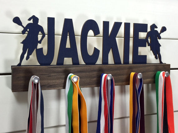  Our personalized lacrosse medal holder is a unique gift for the lacrosse player in your life. This display will be the perfect way for her to show off all of her well-deserved awards. This design comes in a variety of colors, or you can pick from our other choices of sports or phrases so we can customize it just the way you want!