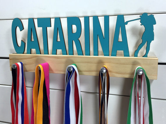  Our personalized golf medal holder is a unique gift for the golfer in your life. This display will be the perfect way for her to show off all of her well-deserved awards. This design comes in a variety of colors, or you can pick from our other choices of sports or phrases so we can customize it just the way you want!