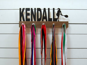  Our personalized tennis medal holder is a unique gift for the tennis player in your life. This display will be the perfect way for her to show off all of her well-deserved awards. This design comes in a variety of colors, or you can pick from our other choices of sports or phrases so we can customize it just the way you want!